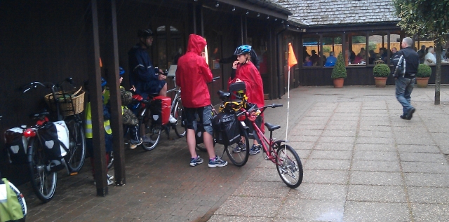 bicycles and cyclists in the pouring rain outside a visitor centre and cafe